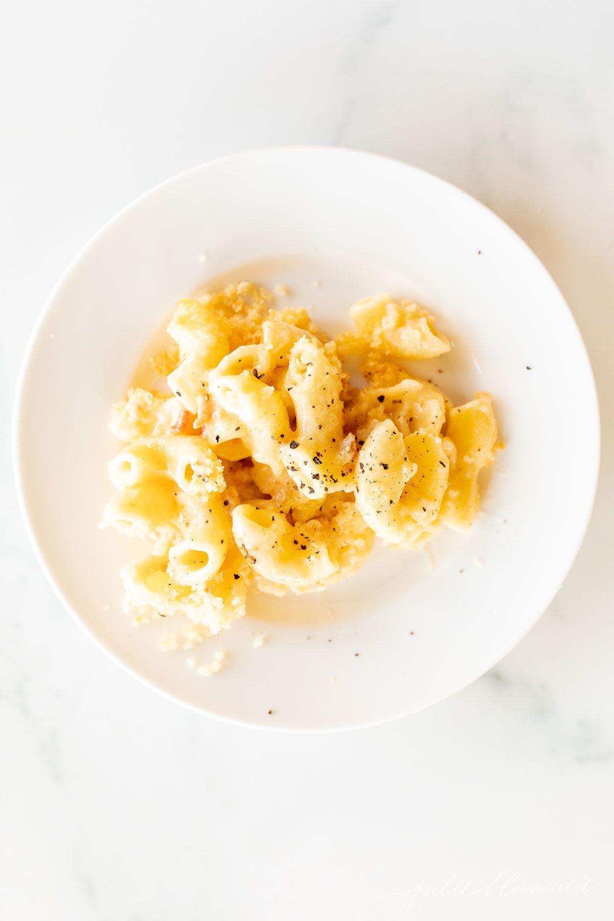 baked mac and cheese on a white plate as a side dish for chicken