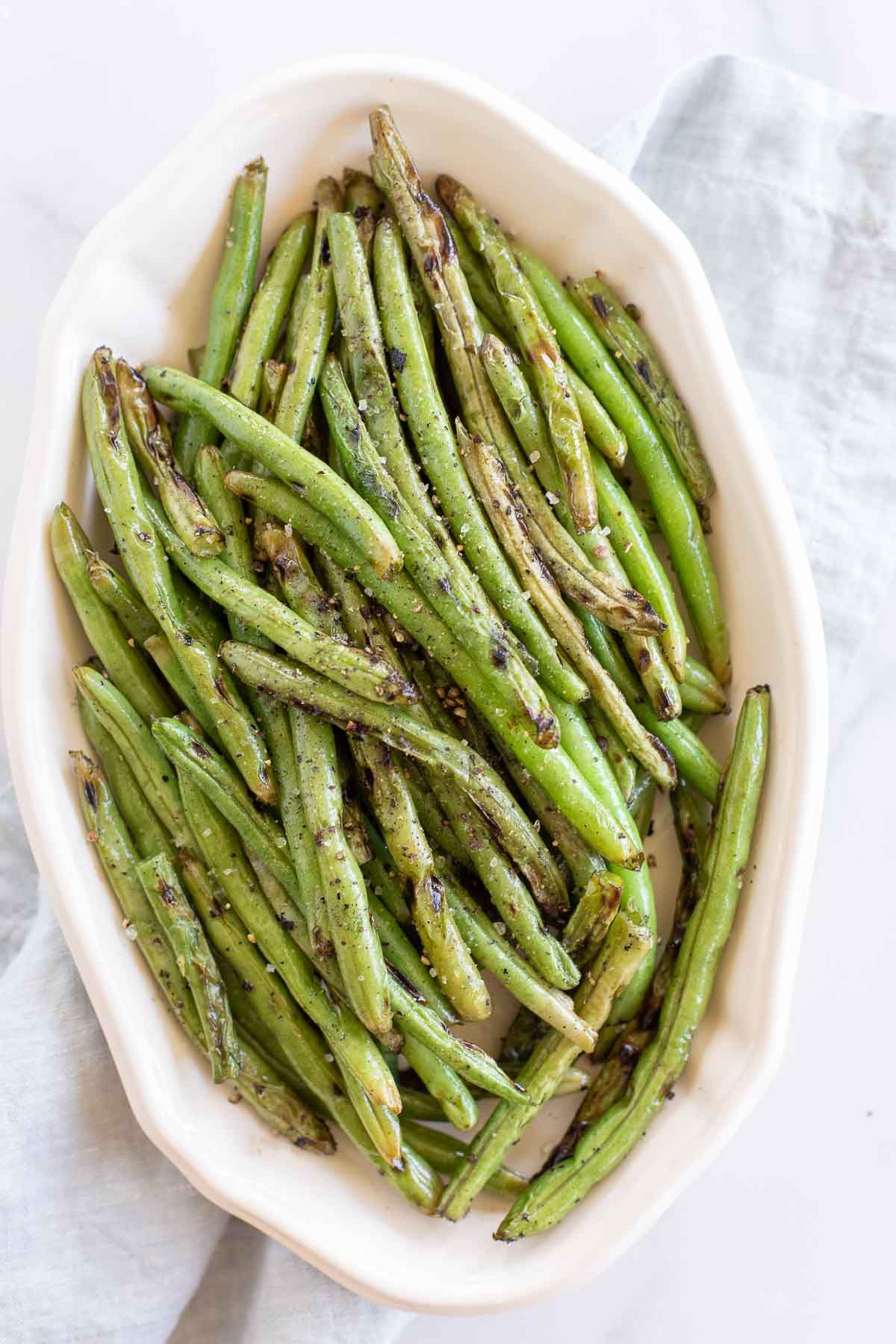 grilled green beans in a white platter to serve as a side dish for chicken 