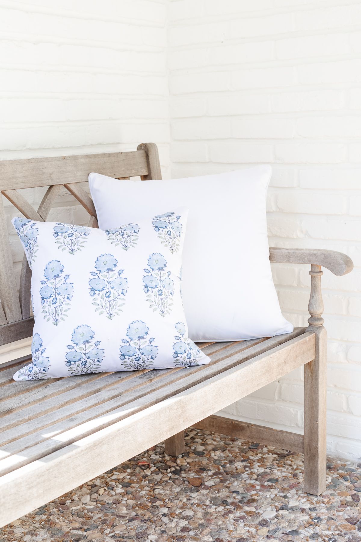 An entryway in a home, with cream walls, and a blue block print Amazon pillow cover resting on a wooden bench.