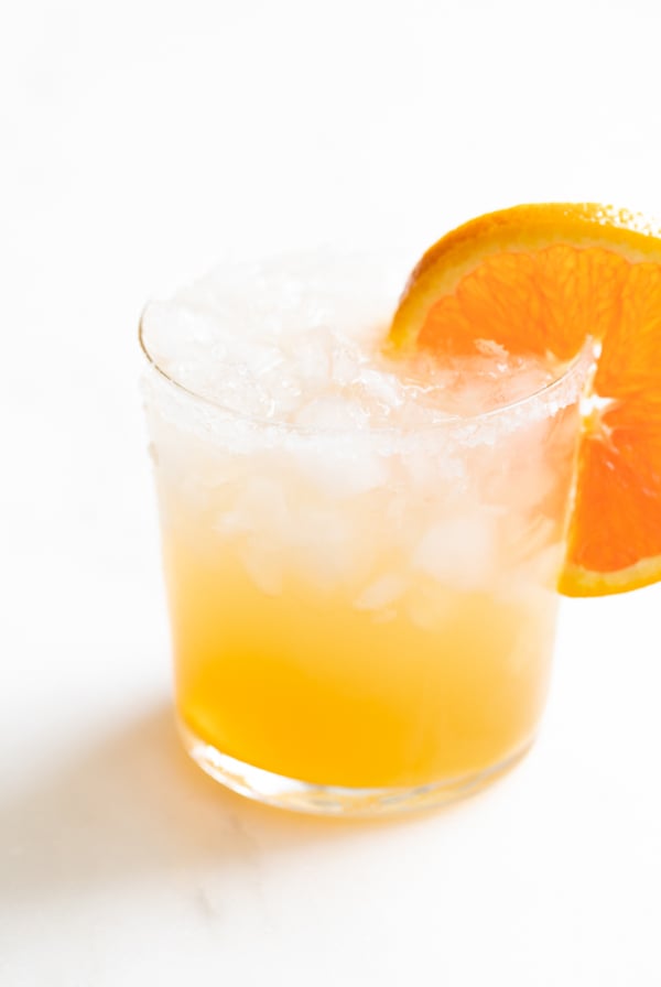 A glass of Cadillac margarita with crushed ice, garnished with an orange slice.