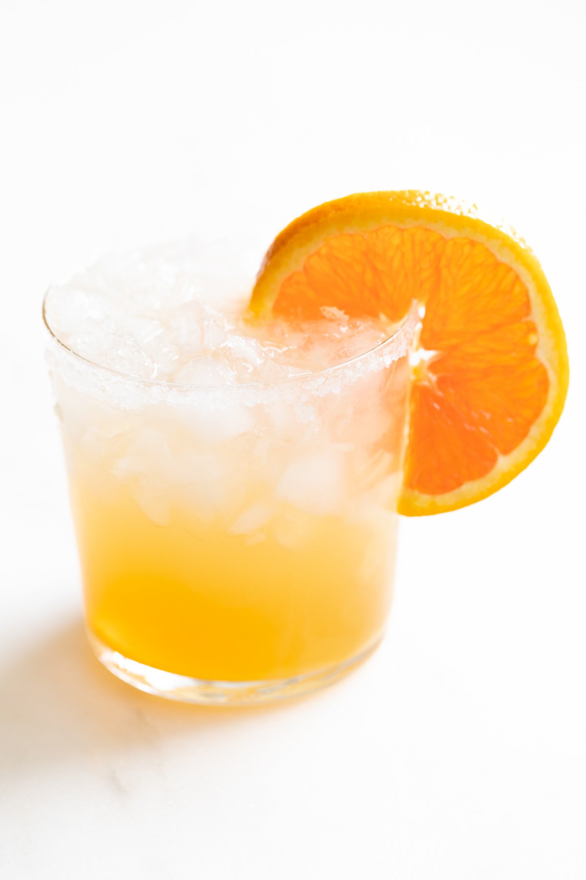 A refreshing Cadillac margarita with crushed ice, garnished with an orange slice.