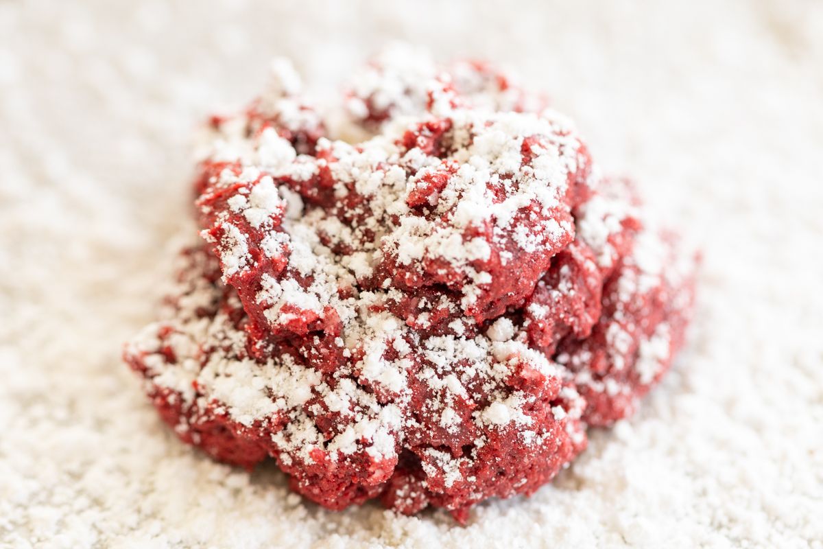 Red velvet gooey butter cookies dusted in powder sugar on a white countertop. 
