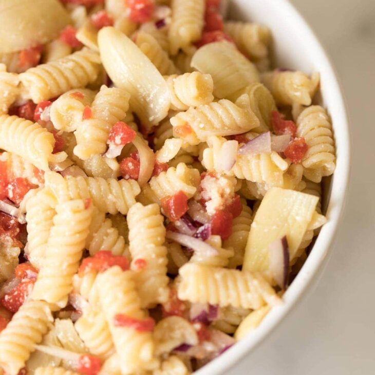 A white bowl full of italian pasta salad