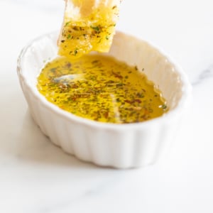 A person is dipping a bread in olive oil for a delicious dip.