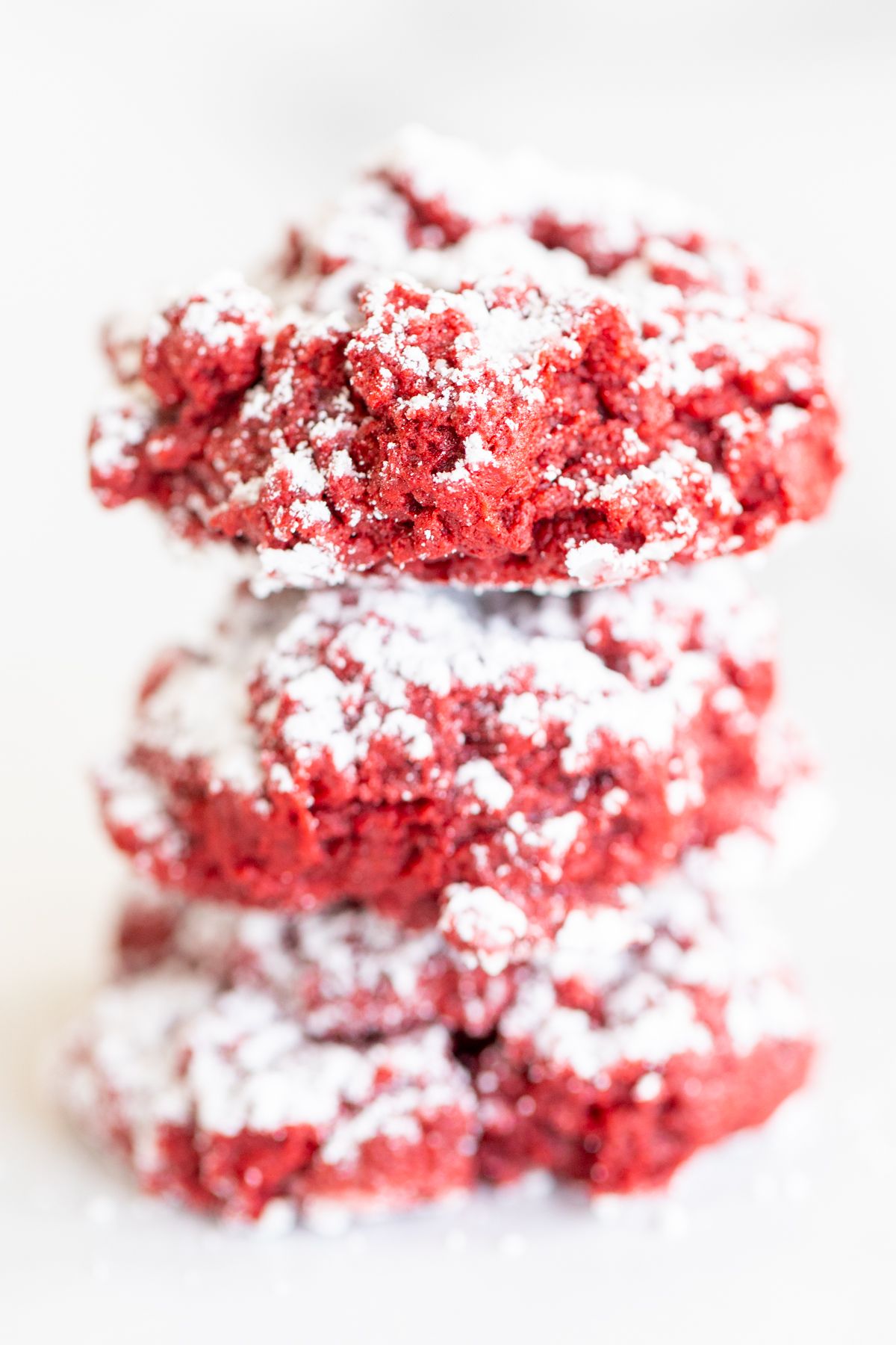 A stack of red velvet gooey butter cookies on a white surface.