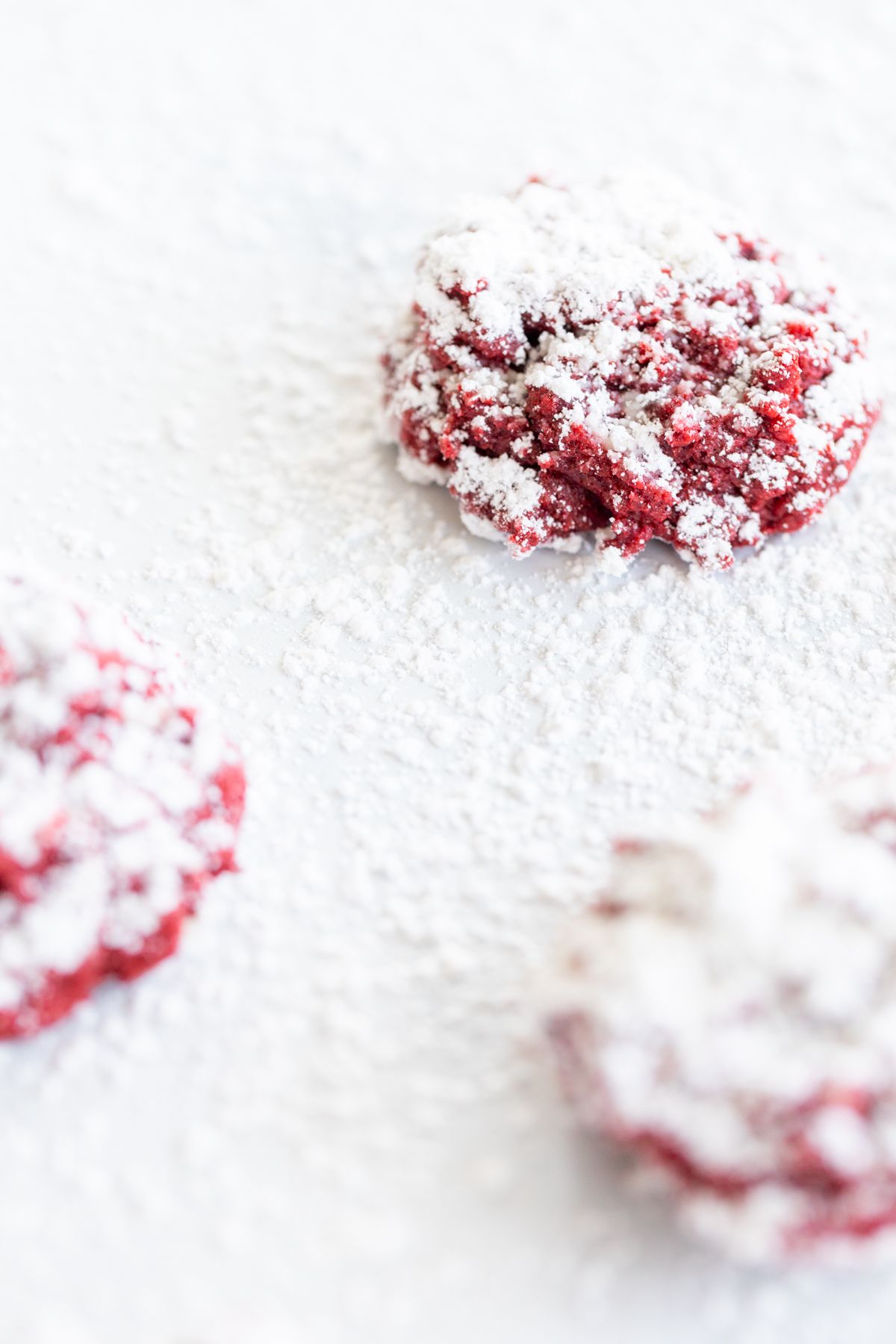 Red velvet gooey butter cookies dusted in powder sugar on a white countertop.