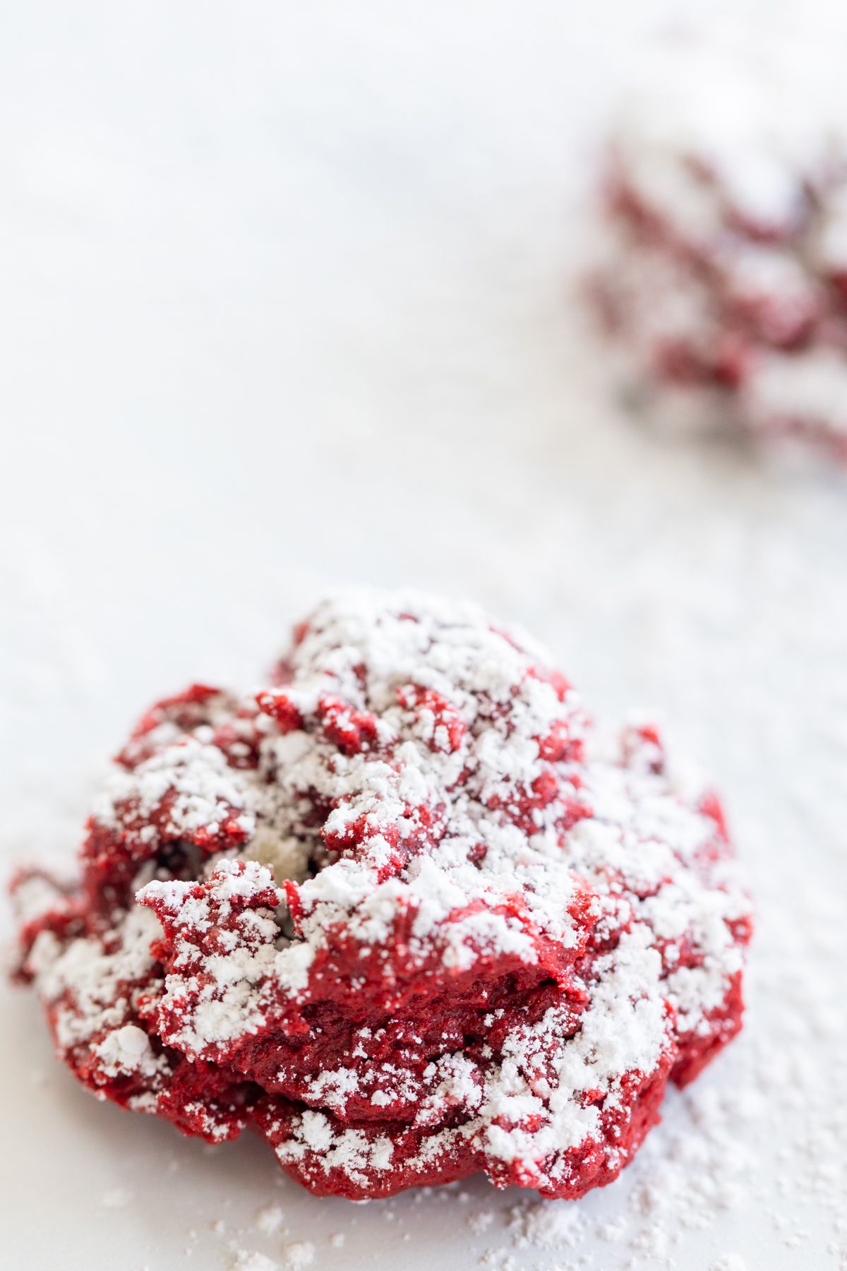 Red velvet gooey butter cookies dusted in powder sugar on a white countertop.