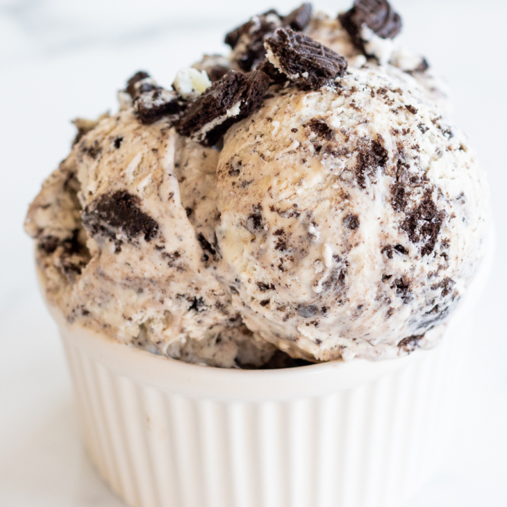 Cookies and cream ice cream scoops in small white bowl, topped with cookie crumbs