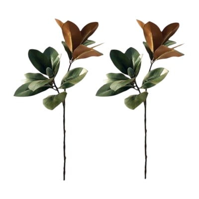 A pair of faux green and brown leaves on a stick, resembling natural foliage.