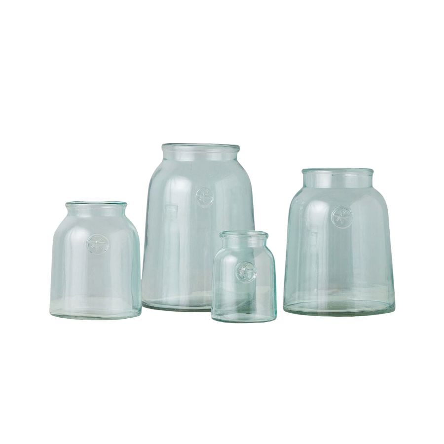 Four clear glass jars of varying sizes, perfect for use as flower vases, are arranged side by side on a plain white background.