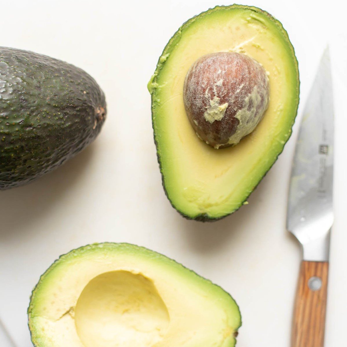 overhead view of a sliced avocado with a knife to the side.