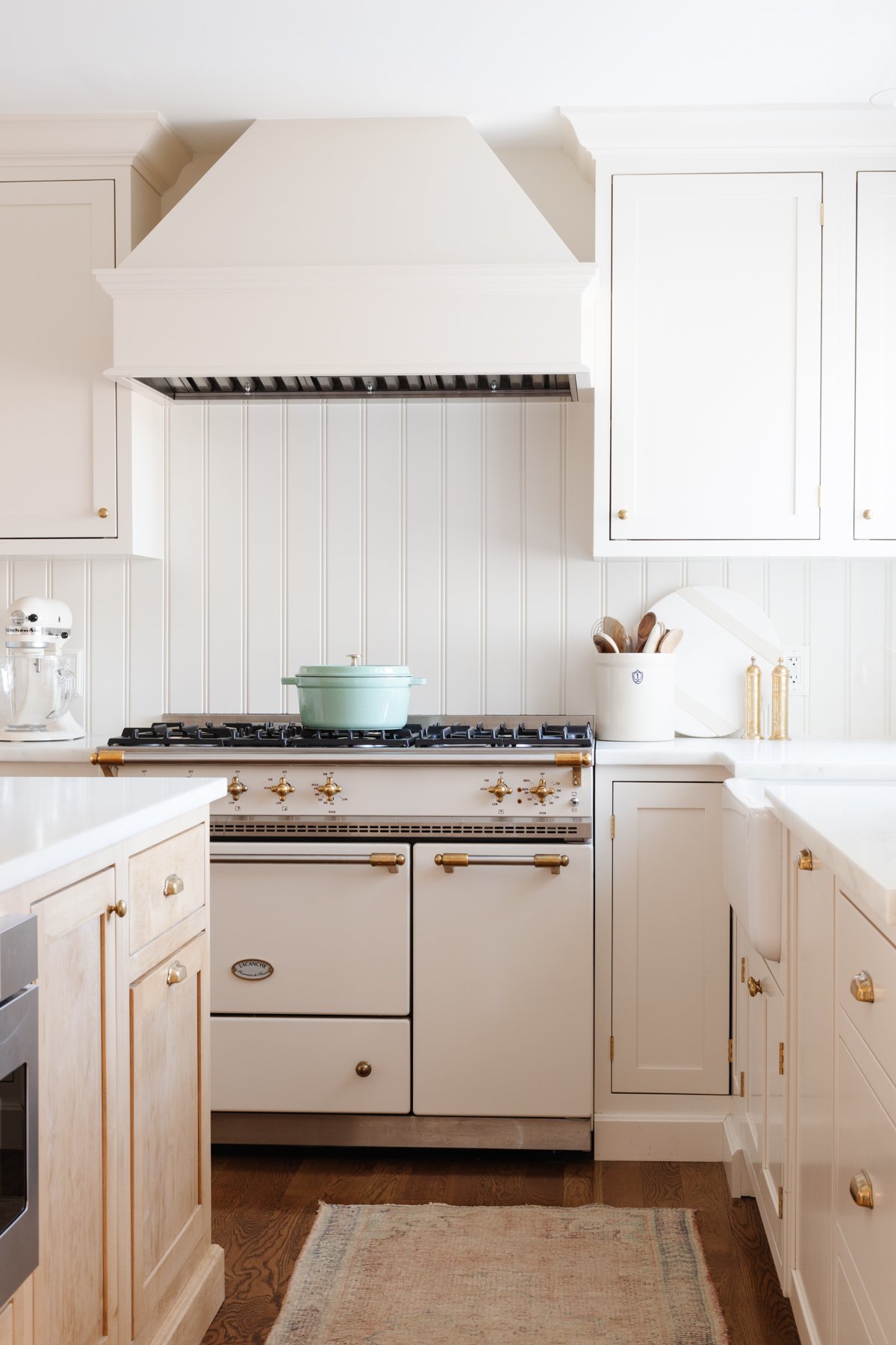 A cream kitchen with a beadboard backsplash and an insert range hood with a wood cover.