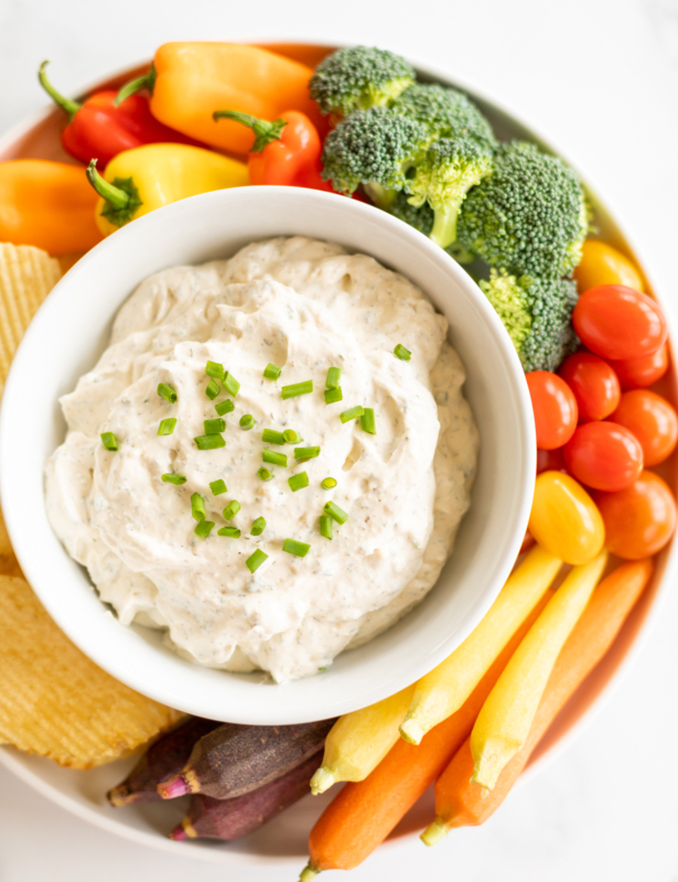 Overhead view of homemade ranch dip in bowl set on tray of fresh vegetables and chips