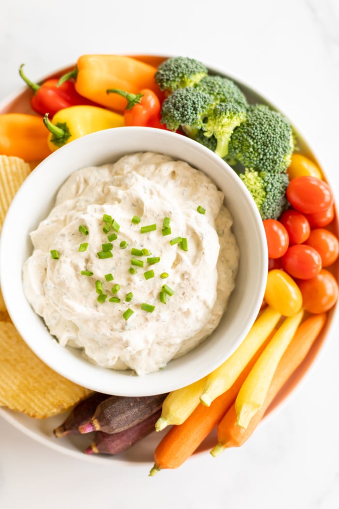 Overhead view of homemade ranch dip in bowl set on tray of fresh vegetables and chips