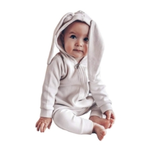 An adorable baby dressed in a white bunny hooded jumpsuit, perfect for Easter basket fillers.