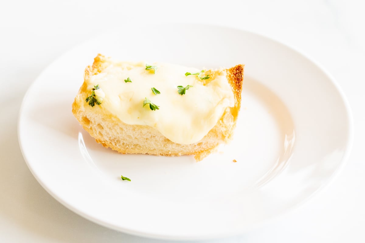 a slice of garlic cheese bread on a white plate