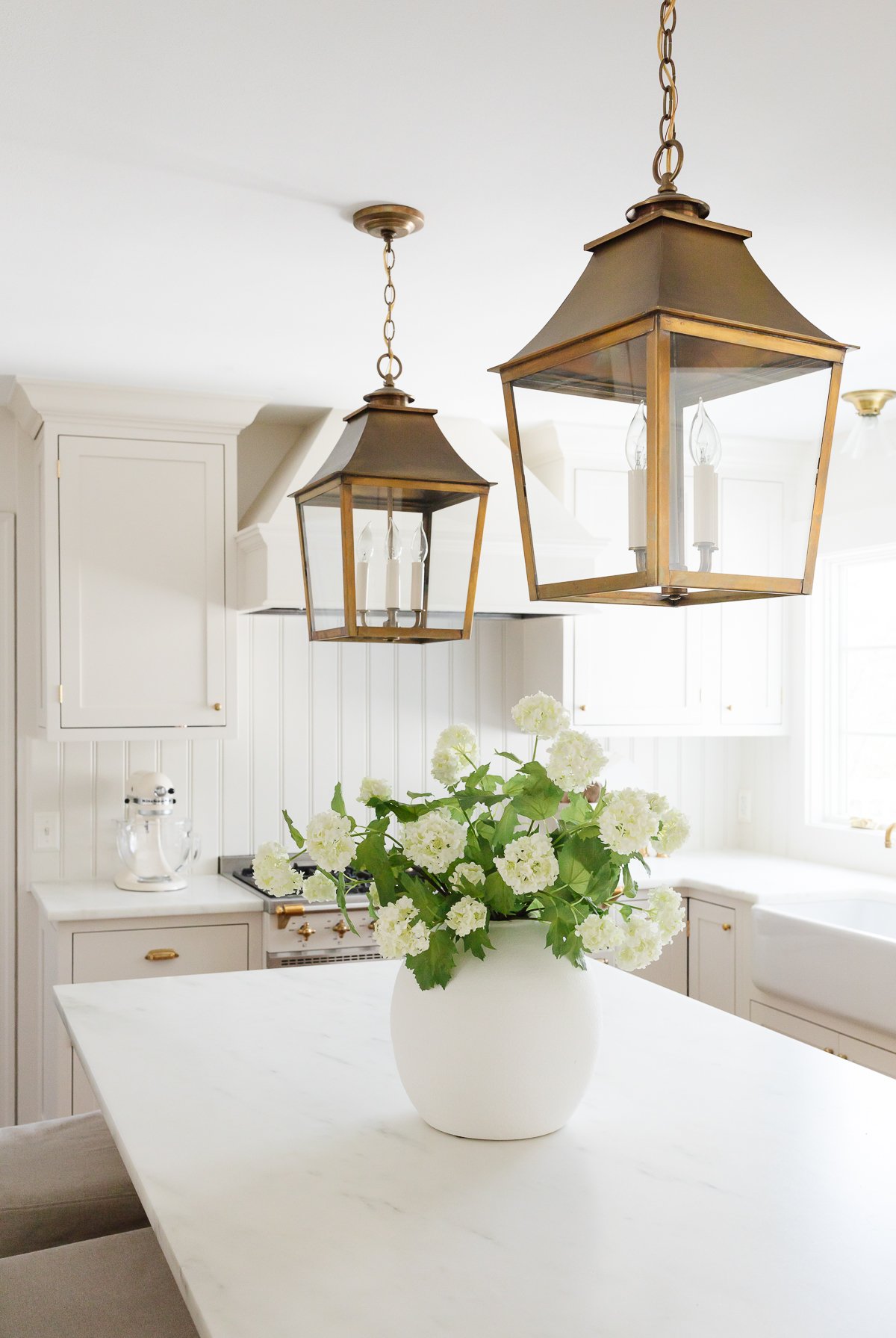 large vase of flowers in cream kitchen with brass light fixtures