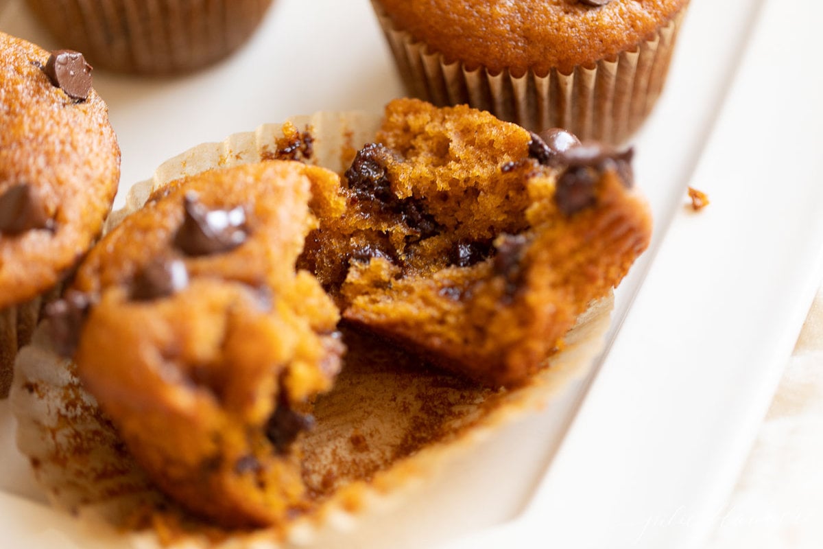 a chocolate chip pumpkin muffin torn in half on a muffin liner.