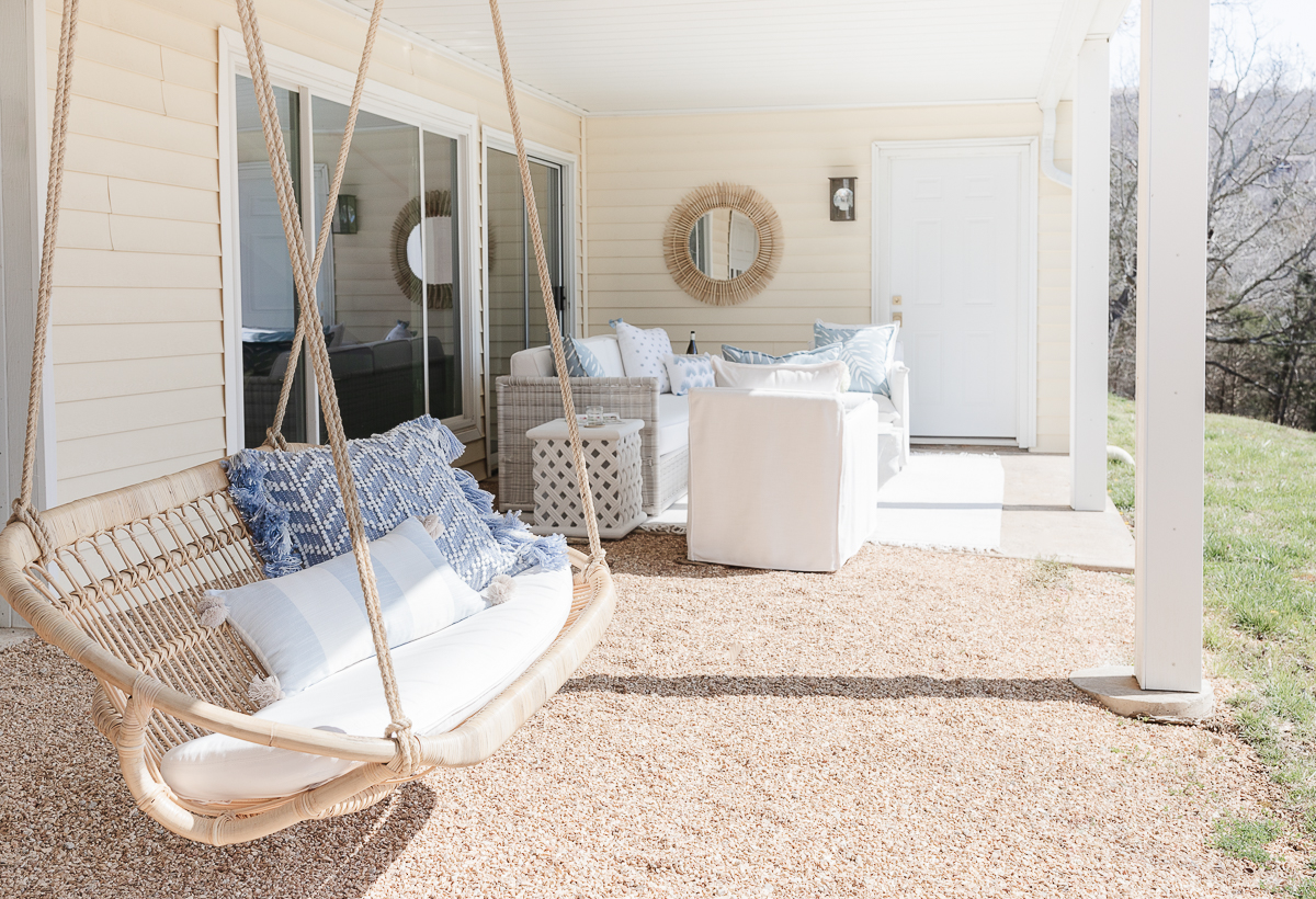 An outdoor patio area with a hanging chair and outdoor pillows in blue and white.