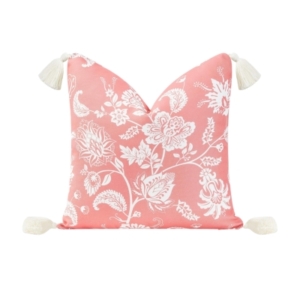 An outdoor pink and white floral pillow with tassels.