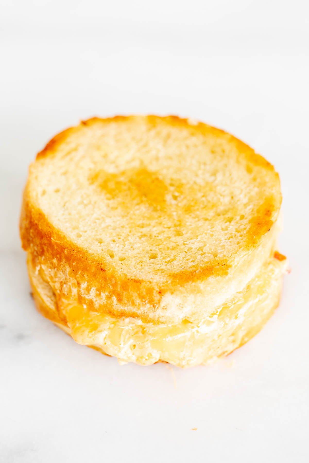 A pimento grilled cheese sandwich on round bread, on a marble countertop.