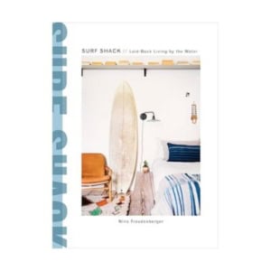 Cover of the book "Surf Shack: Laid-Back Living by the Water" by Nina Freudenberger, featuring a surfboard, chair, decorative books, and bed in a coastal-themed room.