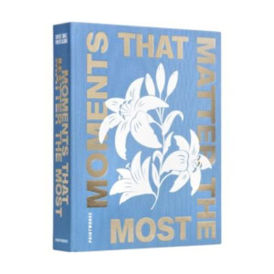 A blue hardcover decorative book titled "Moments That Matter the Most" features gold lettering and a white floral illustration on the front cover.