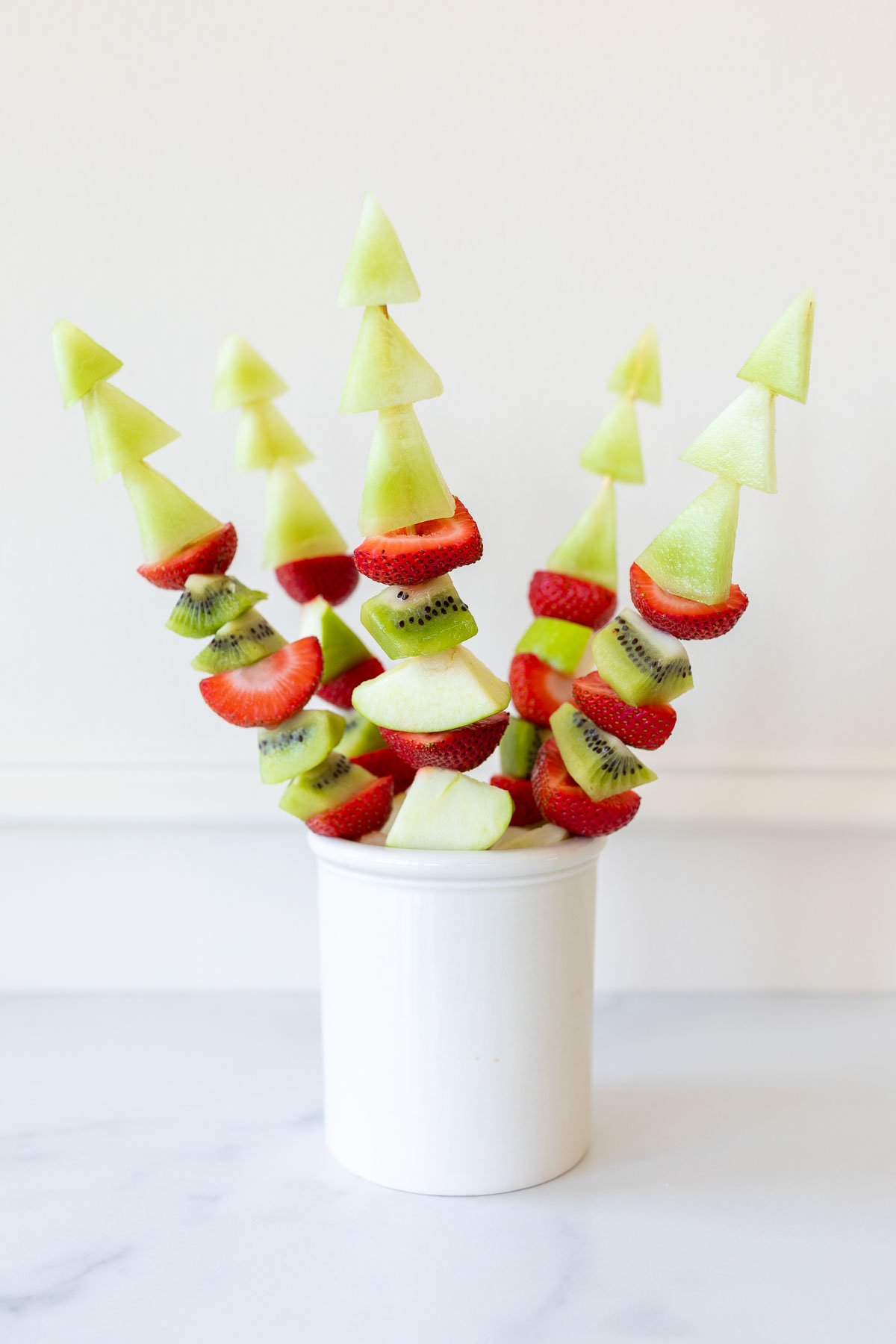 fruit skewers placed in a white container,  in a guide to boat snacks. 