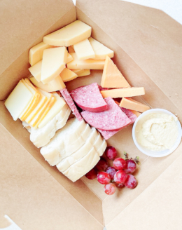 A charcuterie display inside a kraft paper box for a boat snack idea.