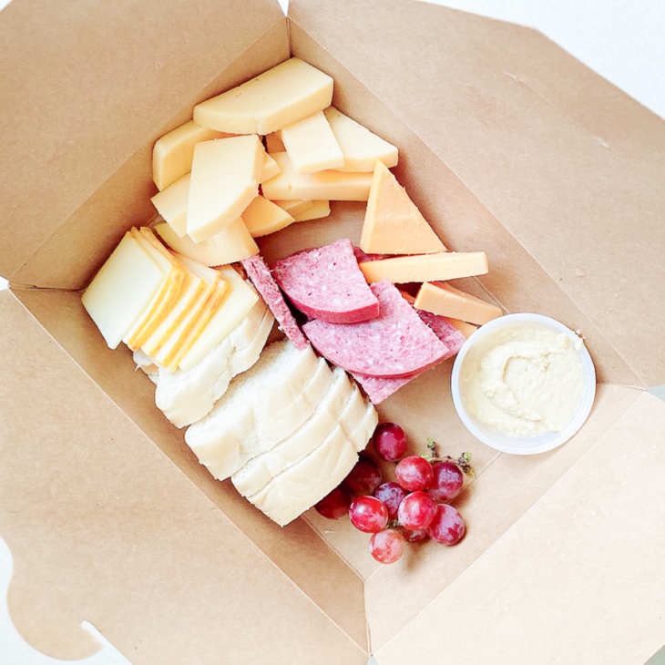 A charcuterie display inside a kraft paper box for a boat snack idea.
