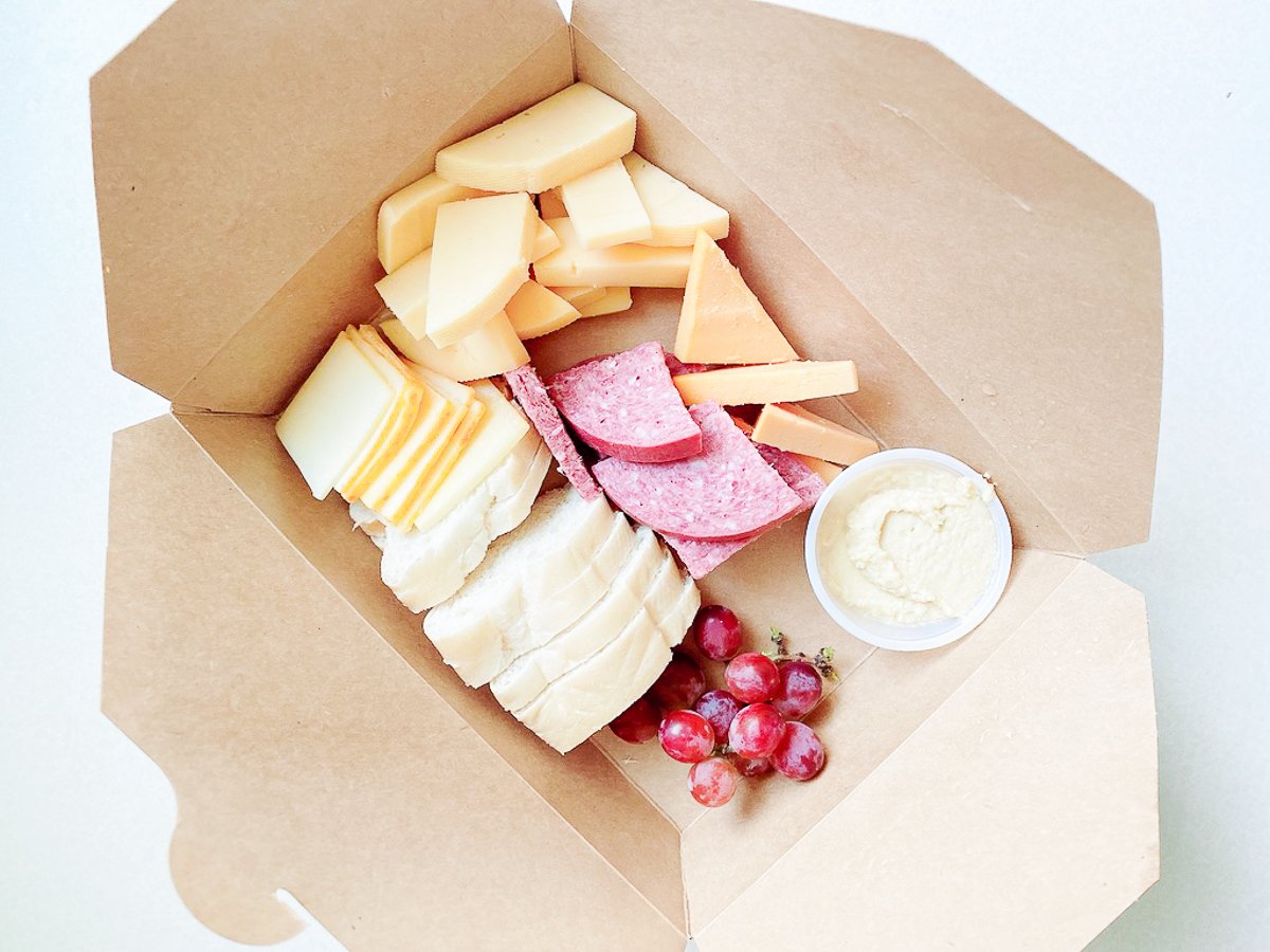 A charcuterie display inside a kraft paper box for a boat snack idea.