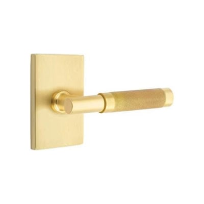 Brass door lever handle mounted on a matching square baseplate against a white background.