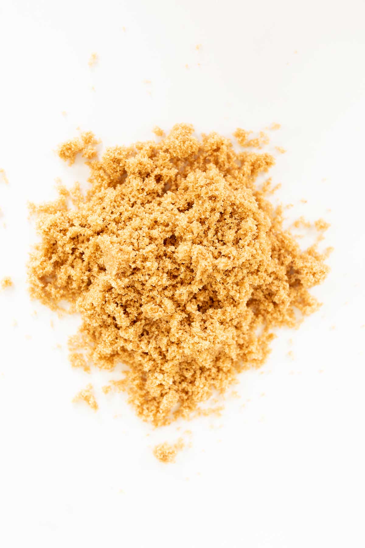 Dark brown sugar scattered on a white surface.