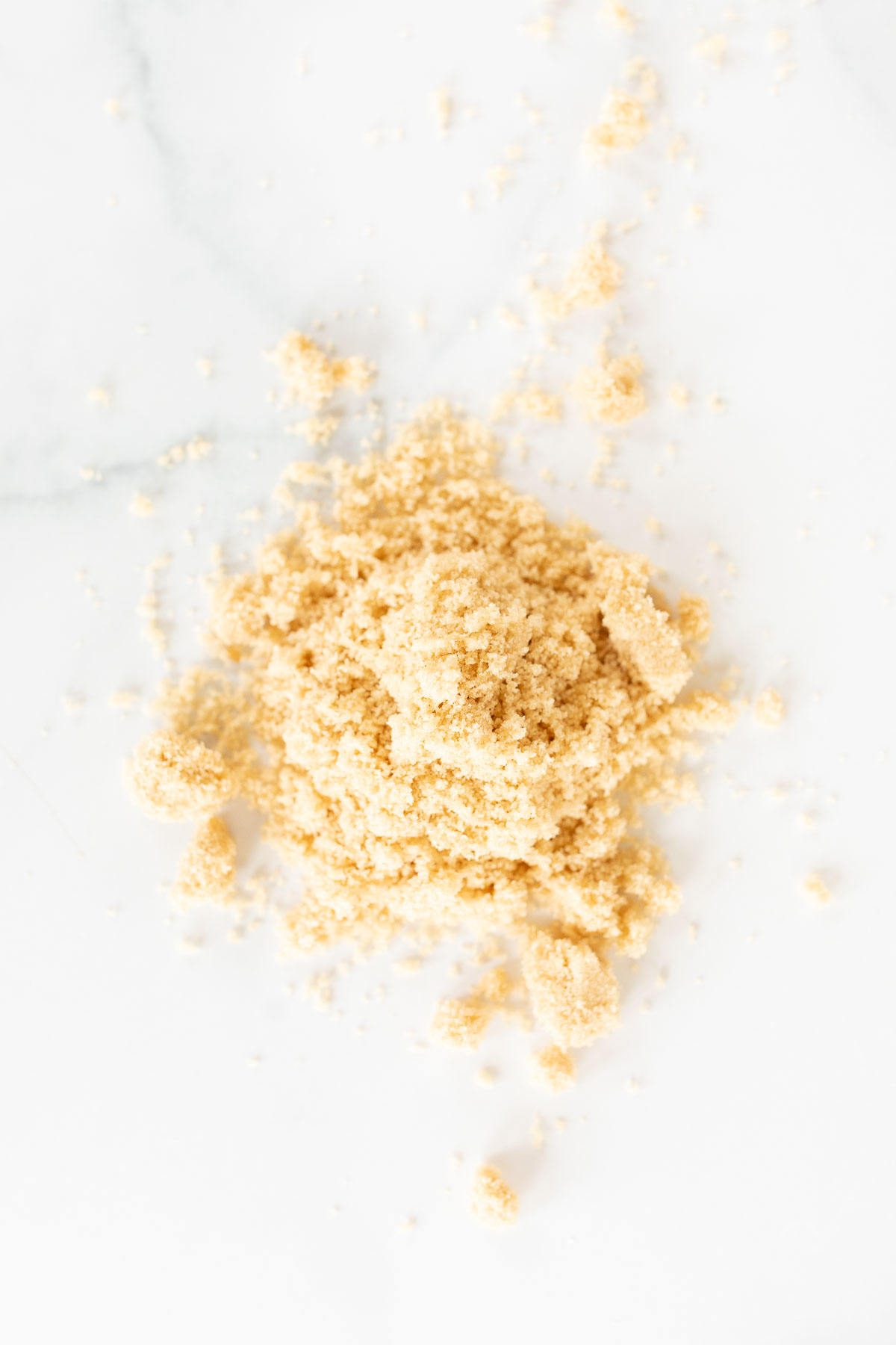 Light brown sugar piled on a white surface.