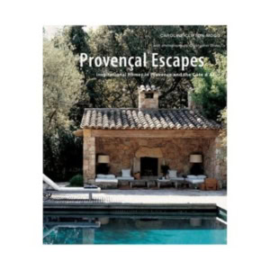 Book cover of "Provençal Escapes," perfect for lovers of decorative books, features a stone outdoor seating area with sofas and a fireplace beside a swimming pool, all surrounded by lush trees.