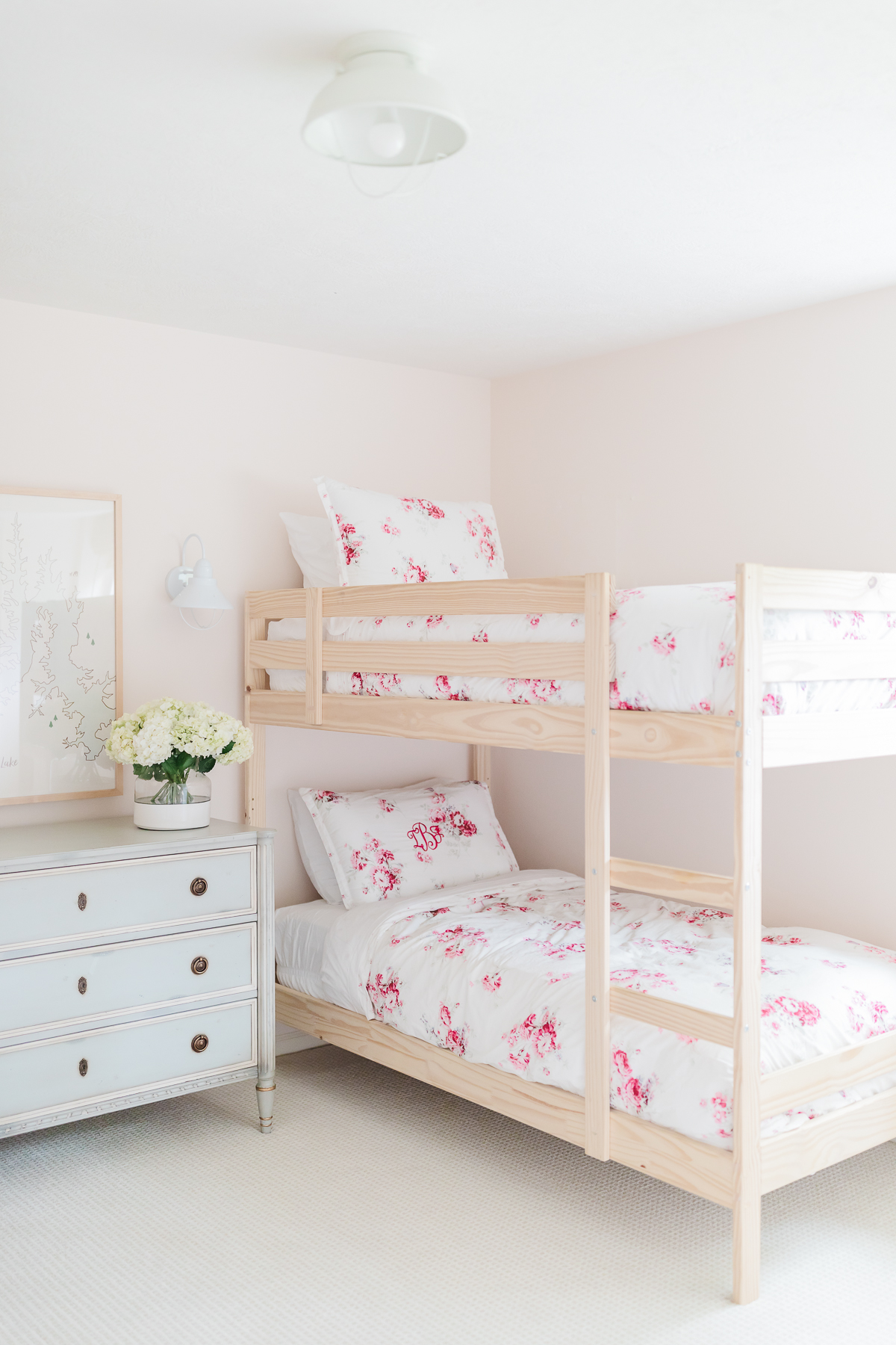 pink bedroom with bunk beds, floral bedding and blue chest of drawers