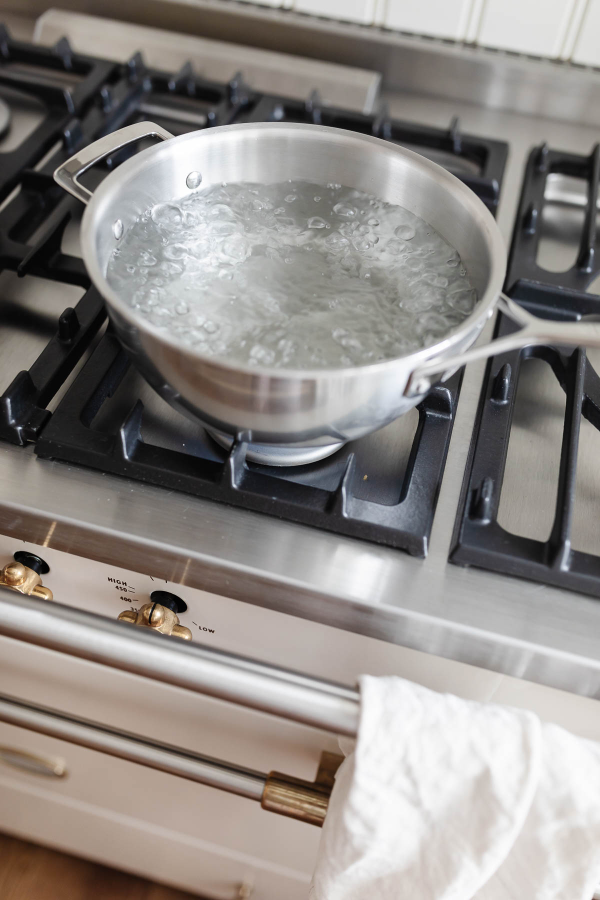 A pot of boiling water on a stovetop in a guide for how to cook pasta.