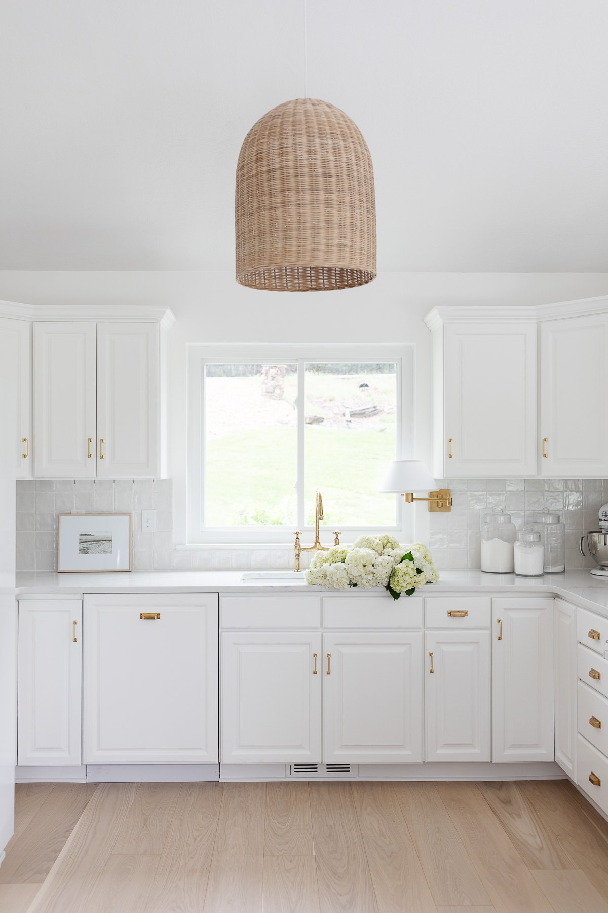 a white kitchen with minimalist decor and a rattan light fixture 