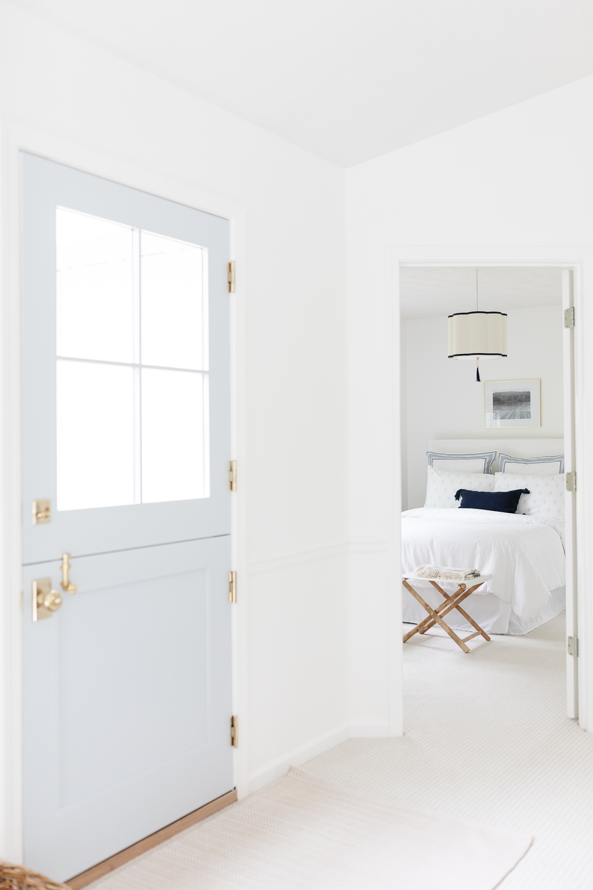 A soft blue Dutch door in an entry of a home with white walls.