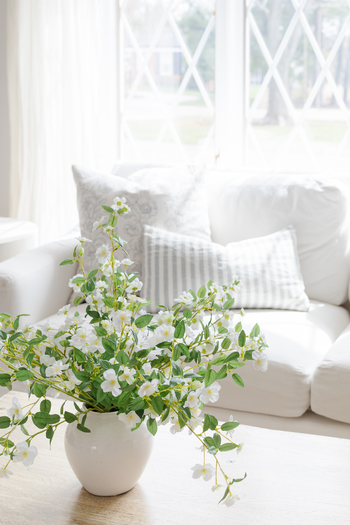 Fresh white flowers on the coffee table of a home with white minimalist decor. 