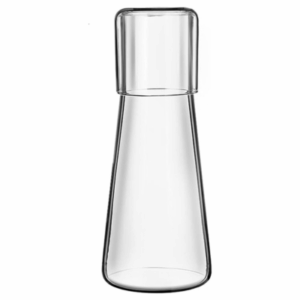 Clear glass carafe with a matching glass cup placed upside down, fitting like a lid on top—an elegant addition to any guest room. The carafe features a wide base and a narrower neck for easy pouring.