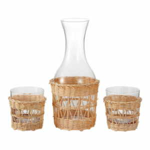 A glass carafe and two glasses, each wrapped with a woven wicker holder, create a charming accent perfect for a guest room, displayed against a white background.