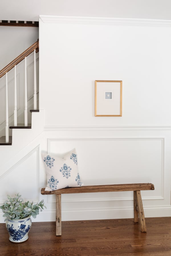 An entryway staircase with molding painted in Sherwin Williams Extra White.