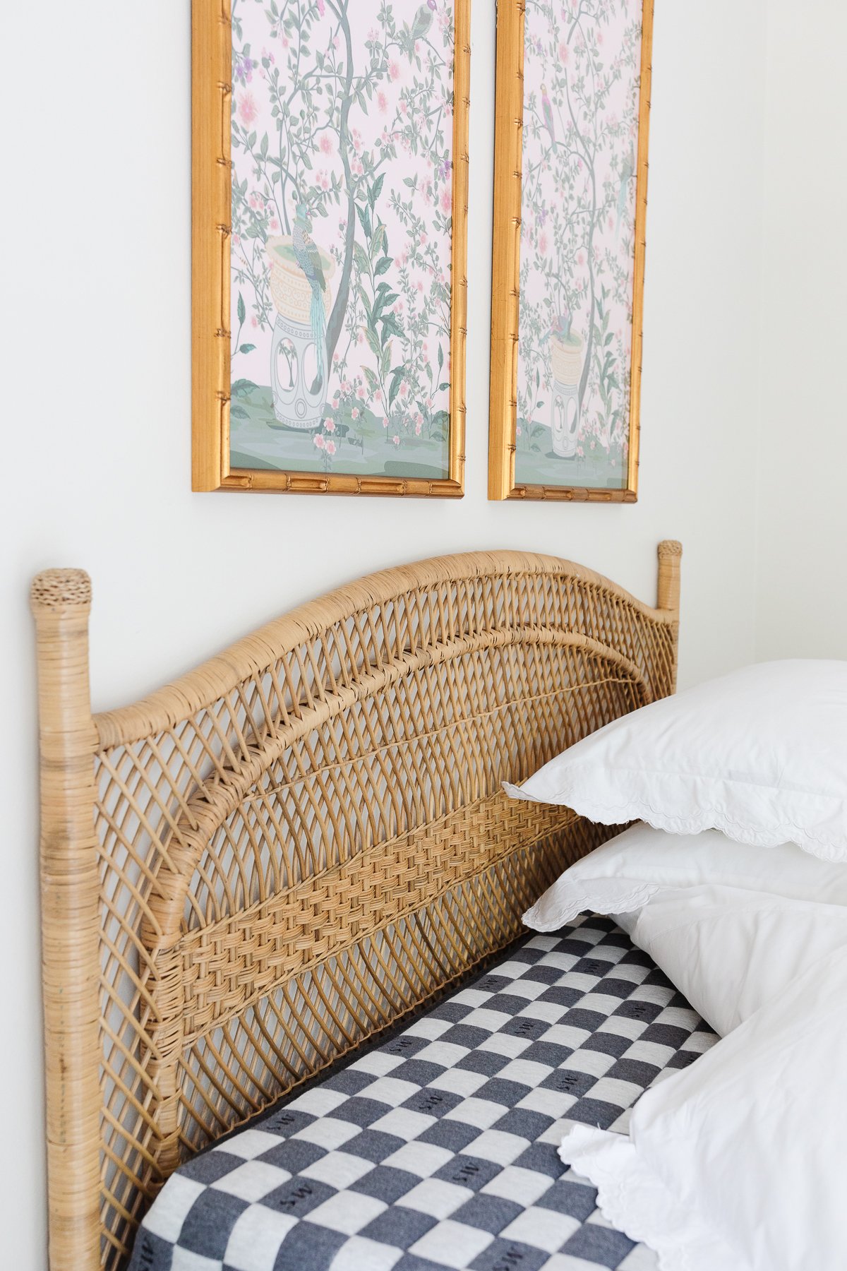 A guest bedroom with a rattan headboard and the bedding pulled back to show a guest room mattress.