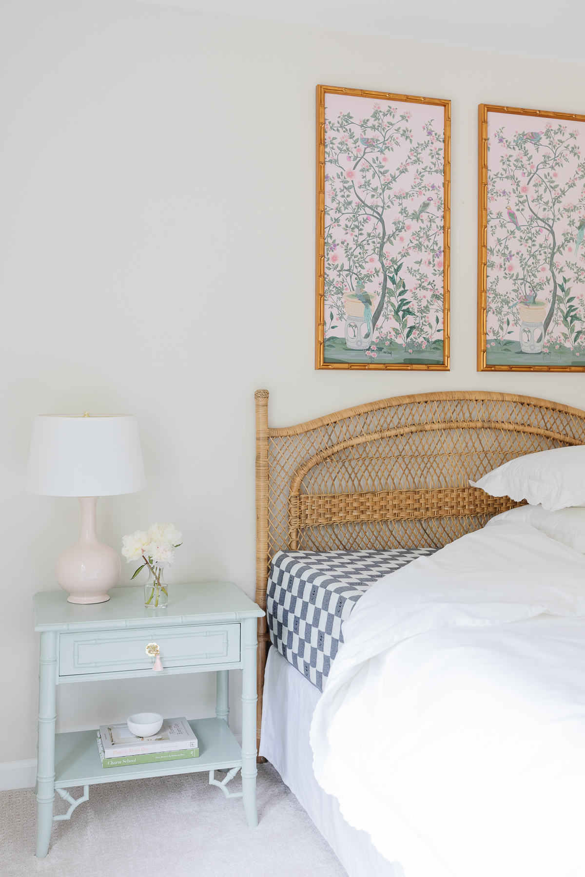 A guest bedroom with a rattan headboard and the bedding pulled back to show a guest room mattress.