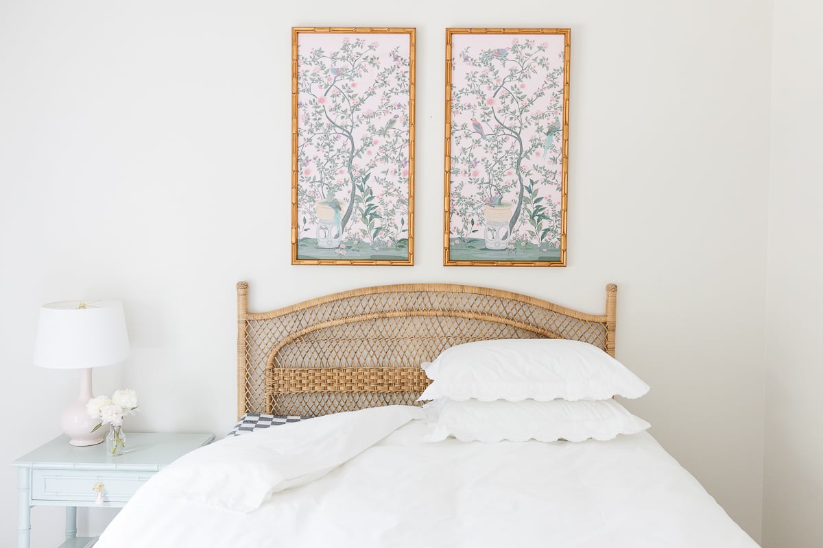 A guest bedroom with a rattan headboard and the bedding pulled back to show a guest room mattress.