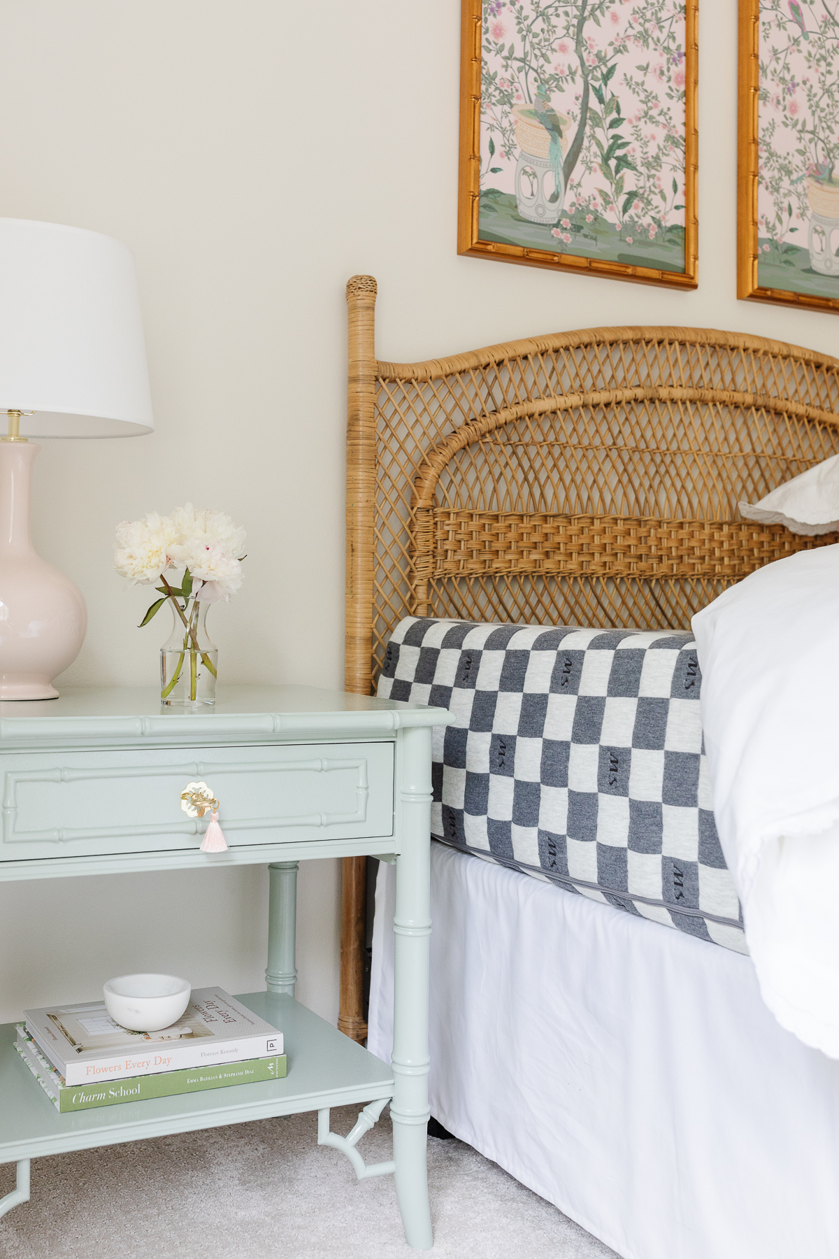 A guest bedroom with a rattan headboard and the bedding pulled back to show a guest room mattress.