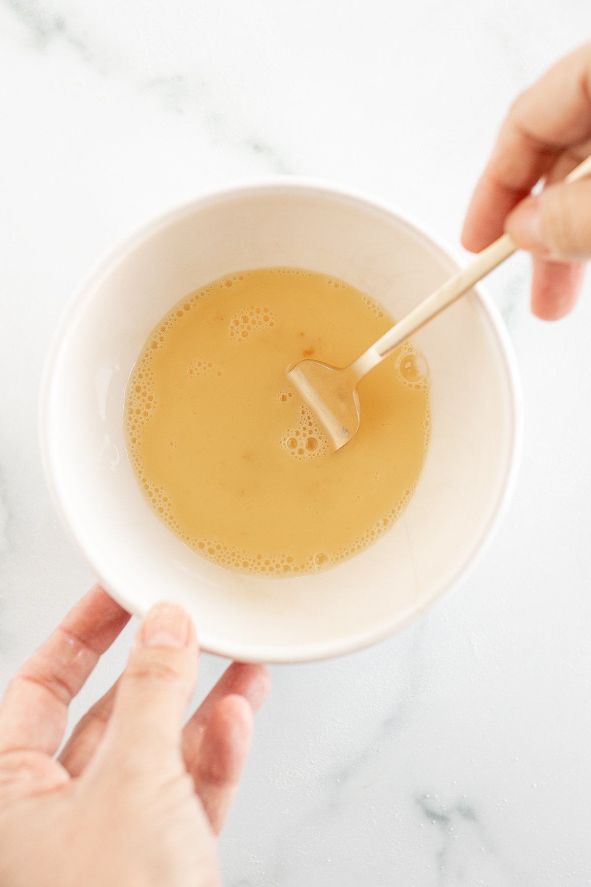 Whisking egg wash in small bowl with fork