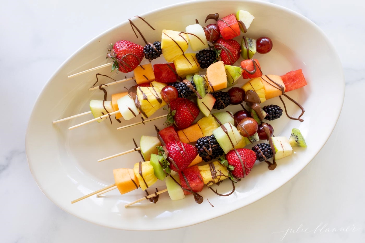 fruit skewers on a white platter