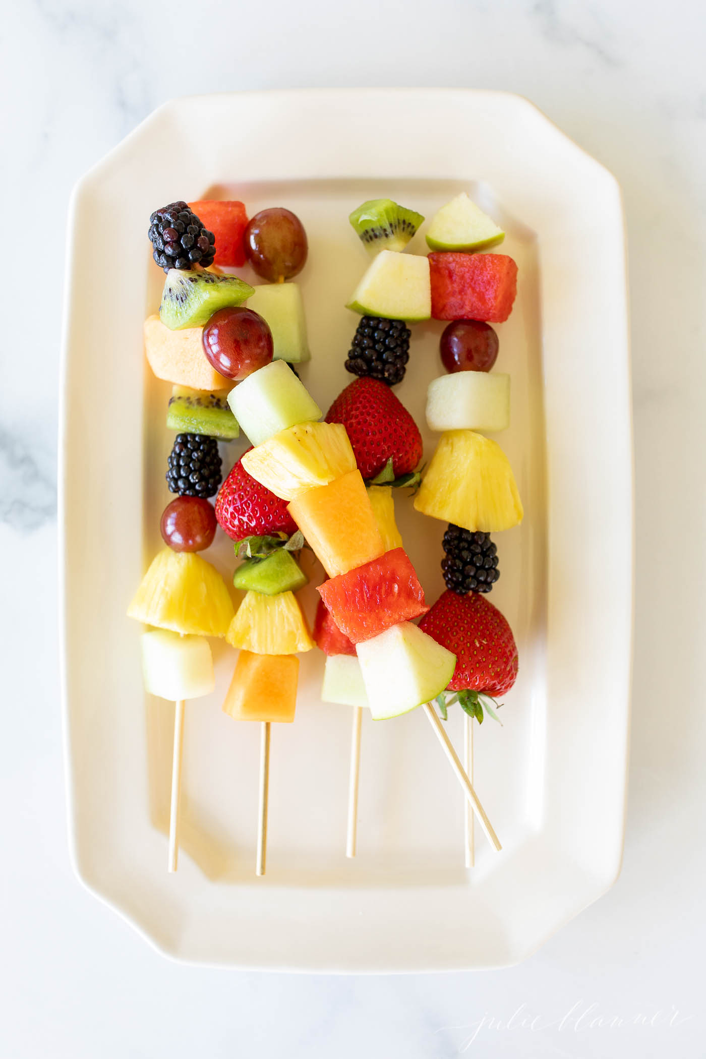 fruit skewers on a white platter